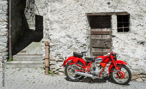 Red Motorcycle on a background of old stone walls and doors. Old