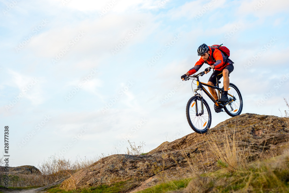 Cyclist in Red Jacket Riding the Bike Down Rocky Hill. Extreme Sport. Cyclist in Red Jacket Riding the Bike Down Rocky Hill. Extreme Sport.