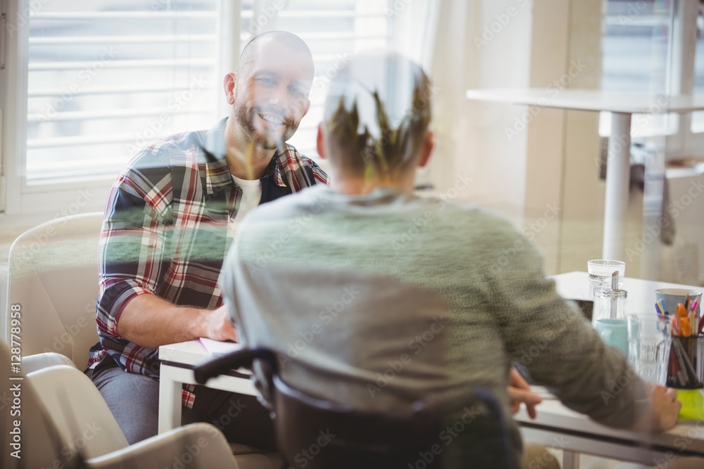 Handicap businessman discussing with colleague in office