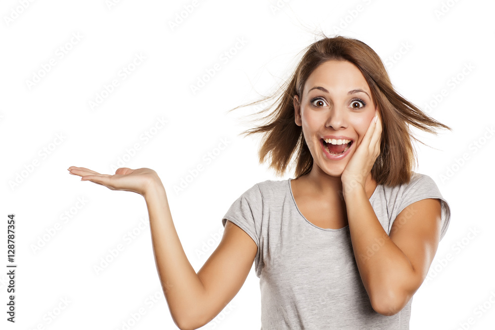young beautiful woman in gray shirt , holding imaginary object on the palm. isolated on white young beautiful woman in gray shirt , holding imaginary object on the palm. isolated on white
