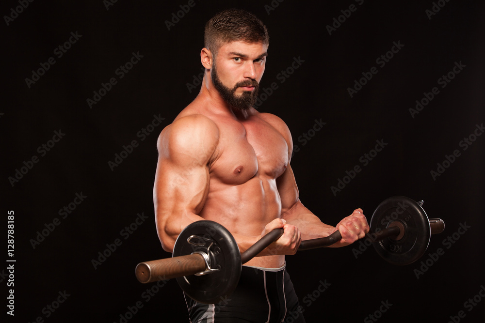 Muscular male athlete is training by lifting the barbell Muscular male athlete is training by lifting the barbell