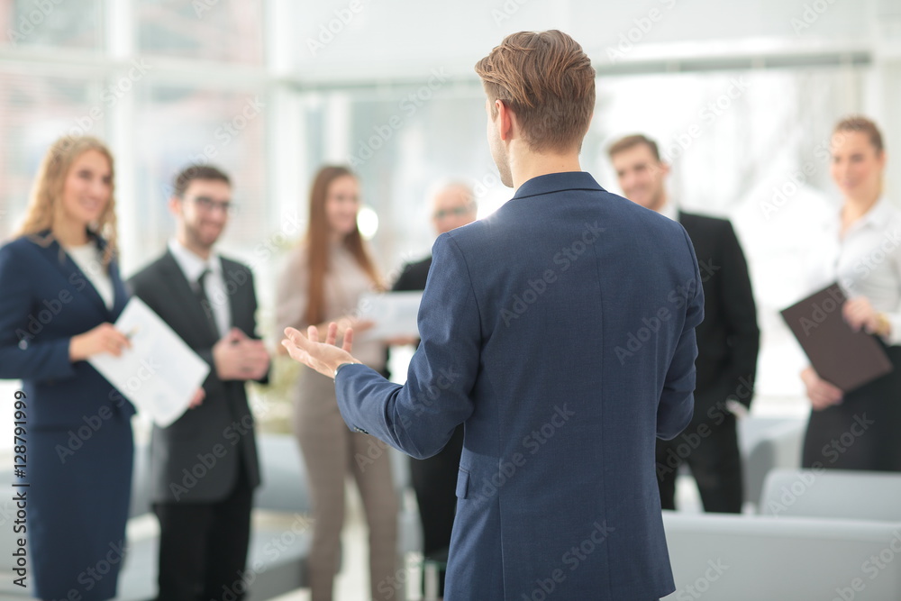 Successful business man standing with his staff in background at