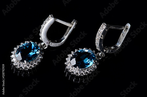 Silver earrings with blue topaz isolated on a black background.