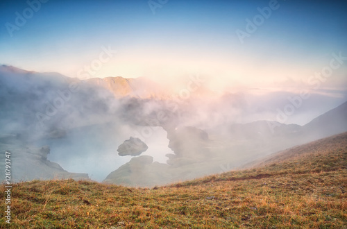 fog over alpine lake at sunrise