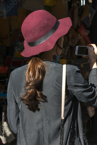 Rear view of woman wearing a hat taking a picture with her phone.