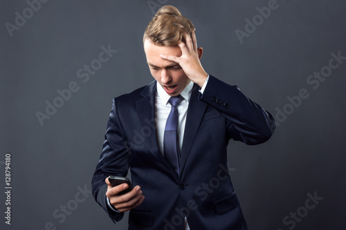 Handsome businessman confused and holding his head standing on gray background