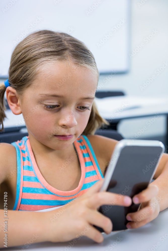 Elementary girl using mobile phone in classroom Elementary girl using mobile phone in classroom