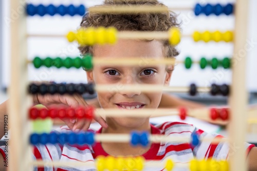 Cute boy playing with abacus in classroom photo