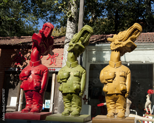 Three sculptures in different colors  with human bodies and Chinese dragon heads.