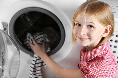 Small girl putting cloth in...