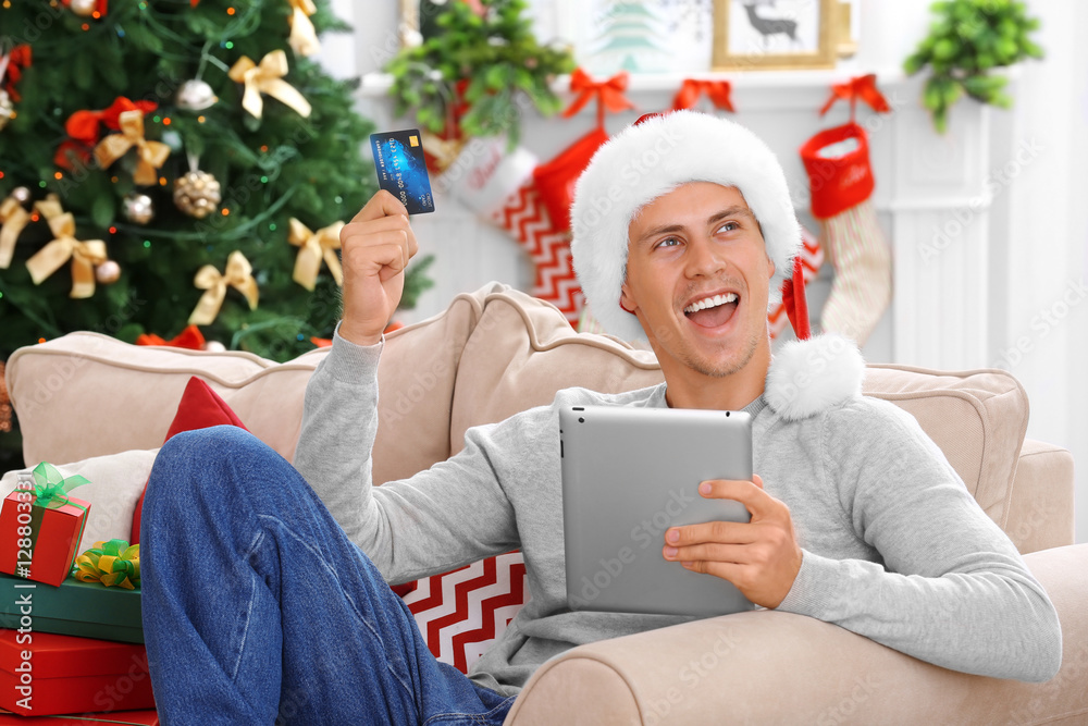 Young man shopping online with credit card at home for Christmas Young man shopping online with credit card at home for Christmas