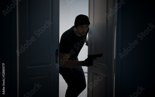 Male thief with gun entering the room © Africa Studio