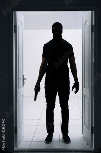 Male thief with gun entering the room