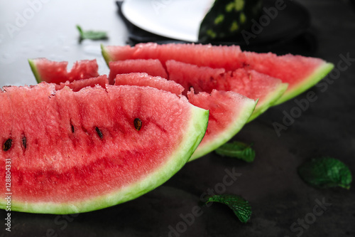 Watermelon slices with mint leaves on table