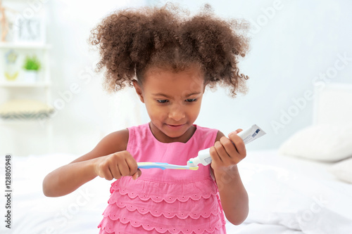 Konstfotografi Cute African American girl brushing teeth in bathroom