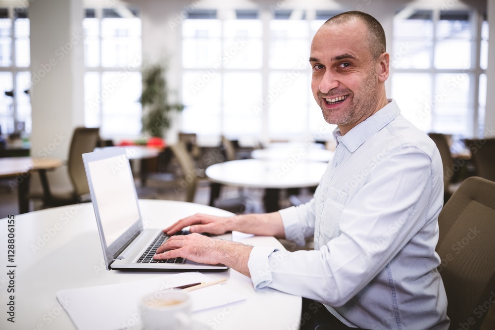 Portrait of happy executive with laptop at creative office