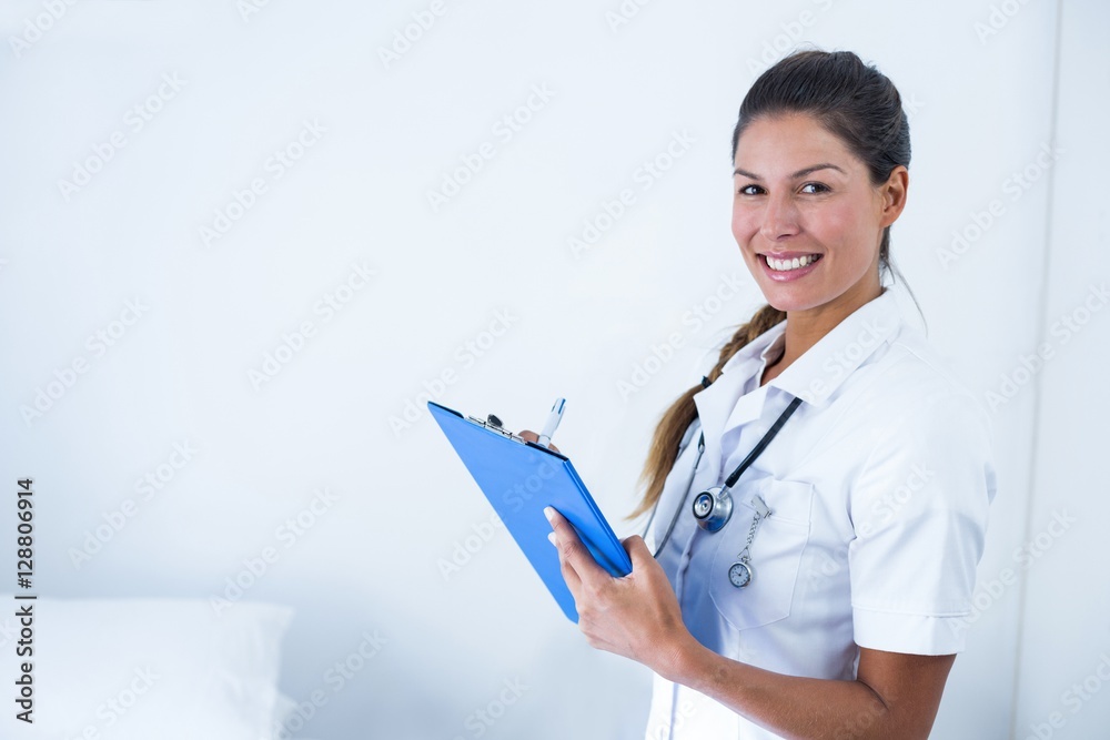 Portrait of female doctor writing on clipboard in hospital Portrait of female doctor writing on clipboard in hospital