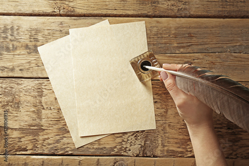 Bild auf Leinwand Female hand writing with feather pen and inkwell on wooden background