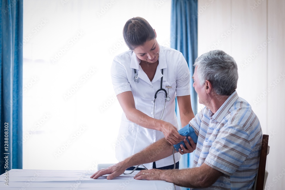 Female doctor checking blood pressure of senior man Female doctor checking blood pressure of senior man
