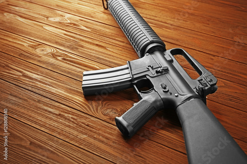 Close up view of assault rifle on wooden background