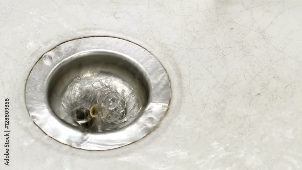 Closeup of water going down the drain in kitchen sink Closeup of water going down the drain in kitchen sink