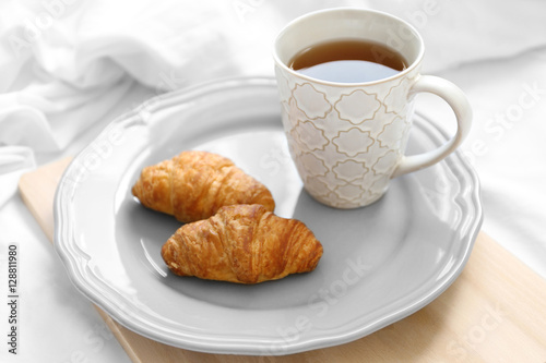 Cup of tea and croissants wooden tray. Breakfast in bed