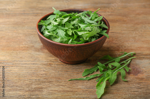 Arugula in a bowl on wooden table