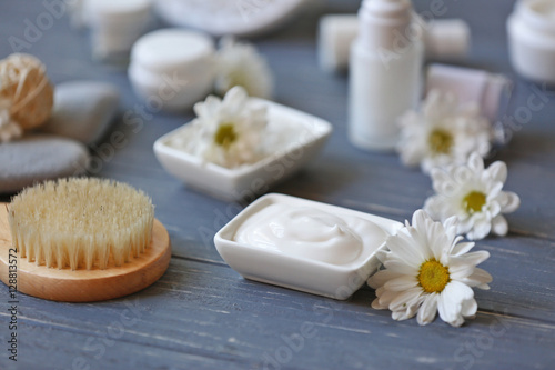 Spa concept. Nourishing cream and daisy flowers on grey wooden table