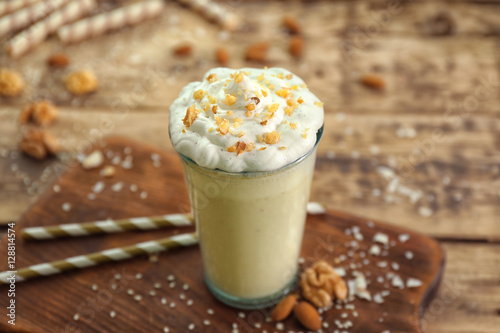 Glass of delicious nut milkshake on wooden background