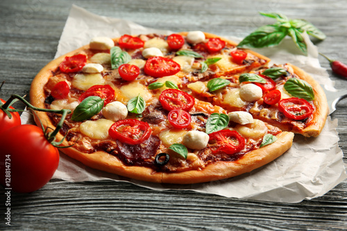 Fresh pizza with tomatoes, cheese and mushrooms on wooden background