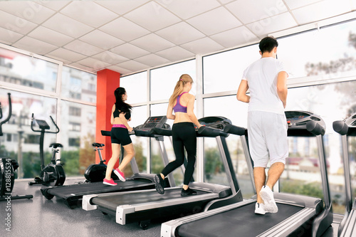 Young people running on treadmills in gym