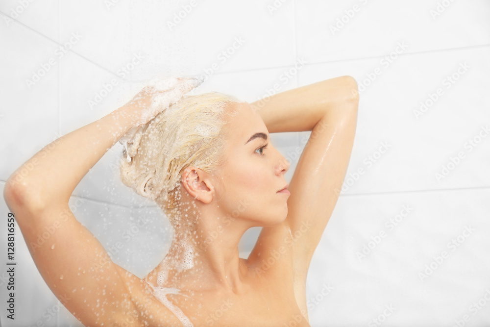 Naklejka premium Beautiful young woman washing head in shower
