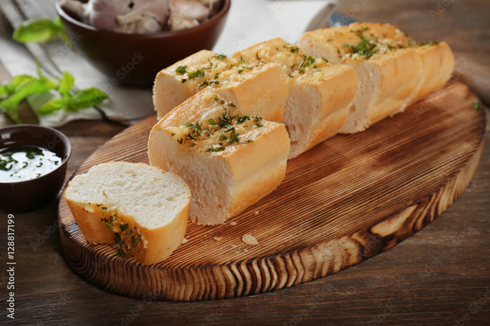 Slices of tasty bread with garlic and herbs on wooden table