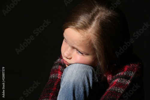 Sad little girl on black ba...