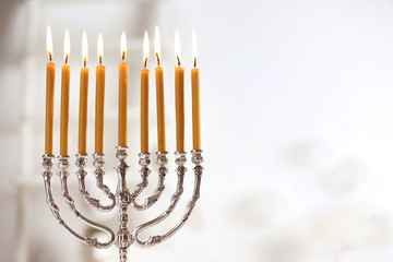 Beautiful menorah with burning candles on light blurred background. Hanukkah concept