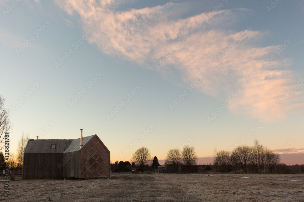 Dramatic wintry scene with snowy Wooden house and pink sky