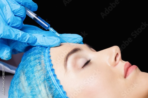 Woman receiving botox injection on her forehead