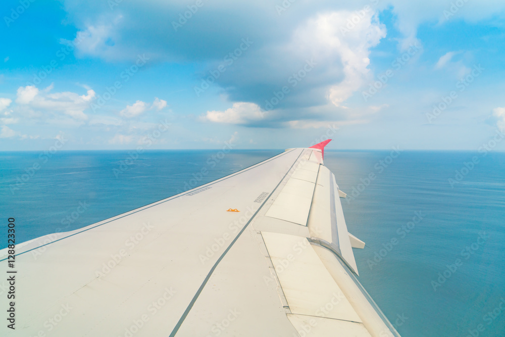 Obraz premium Airplane descending over a blue ocean to maldives island .