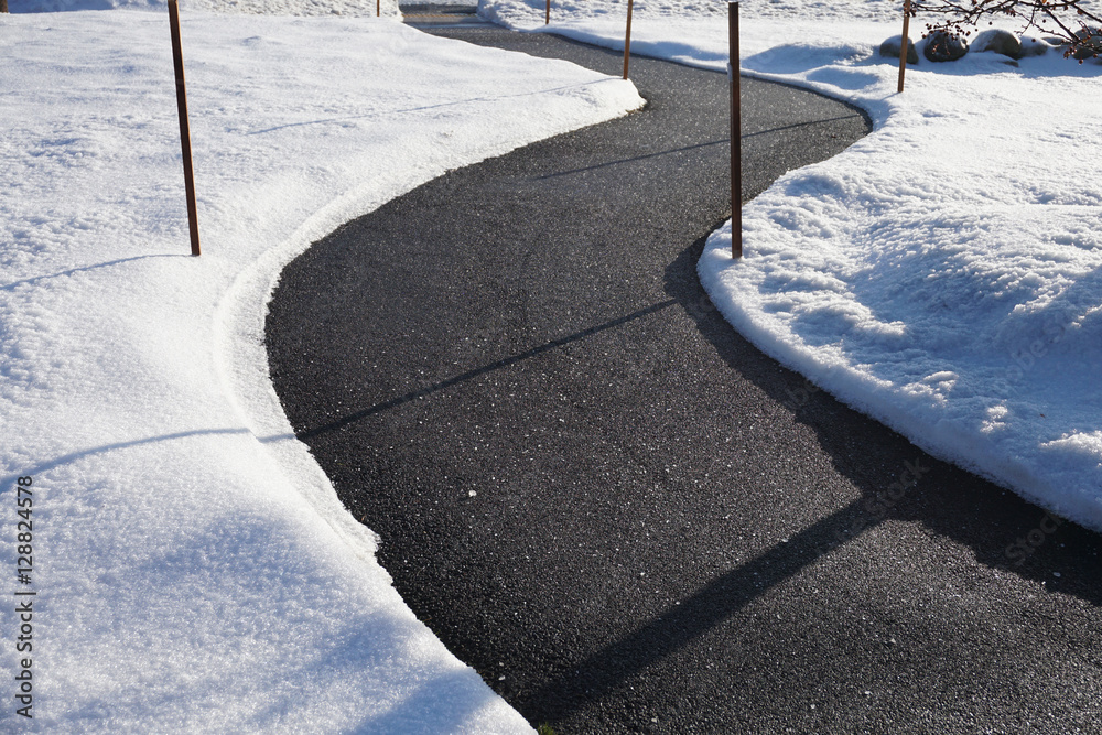 Naklejka premium winding sidewalk after snow with snow removed