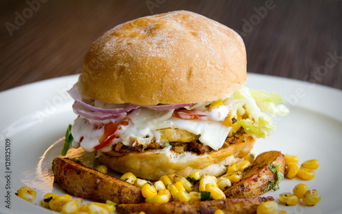 Canvas Print Side view of a healthy egg burger with mayo, corn, potato wedges and more