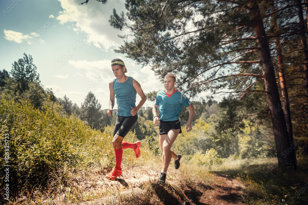 Trail running athletes crossing off road terrain at sunny day Trail running athletes crossing off road terrain at sunny day