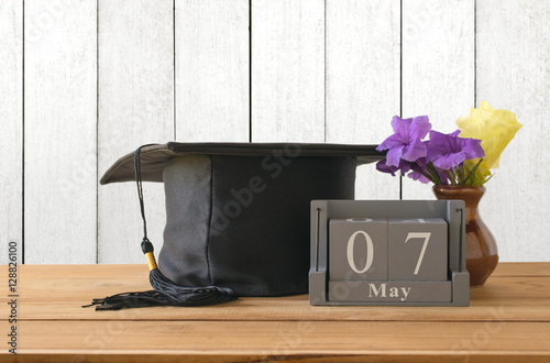 graduation cap, hat with vintage wooden calendar set on the 7 of photo