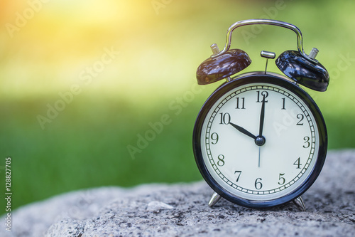 clock in the green nature background, retro bell clock time at 10 o'clock. photo