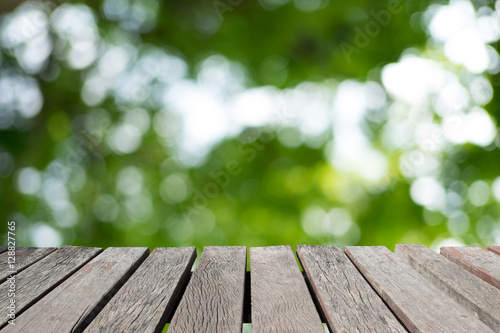 Wooden floor or wooden planks with blur image of light streaming through leaves.