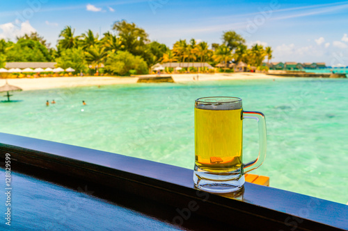 A glass of beer with Beautiful tropical Maldives island .