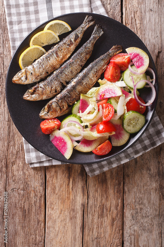 grilled sardines with fresh vegetable salad close-up. vertical top view