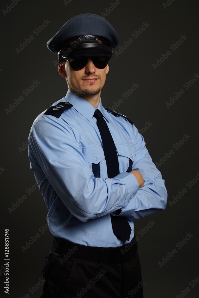 Portrait of young policeman in uniform on gray background Portrait of young policeman in uniform on gray background
