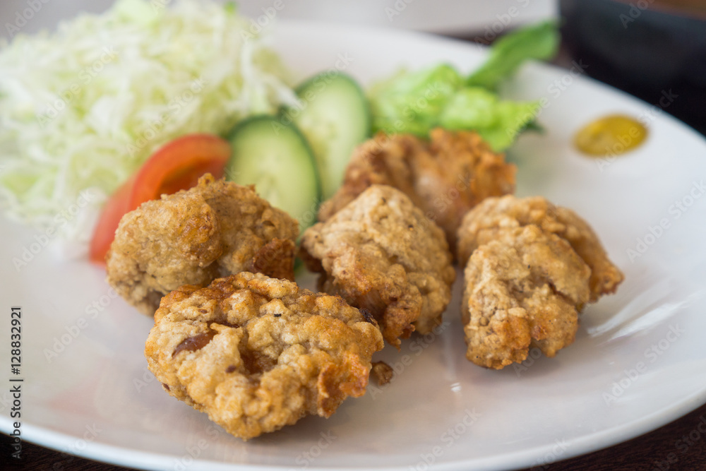 Japanese style deep fried chicken, crispy fried chicken in white plate with cabbage, cucumber and tomato for salad Japanese style deep fried chicken, crispy fried chicken in white plate with cabbage, cucumber and tomato for salad