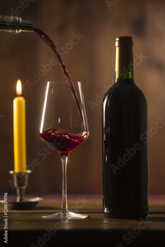 Pouring red wine into wineglass from green bottle