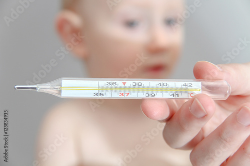 One year old sick baby boy at the young female doctor, temperatu photo